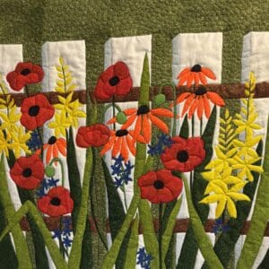 Bright flowers bloom vividly against a white picket fence.
